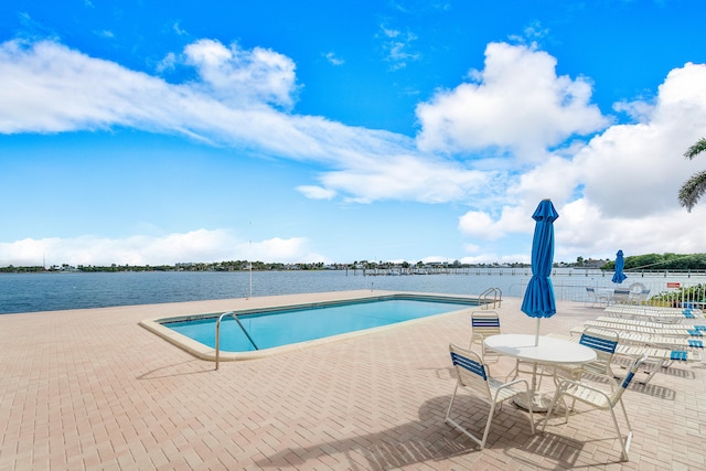 view of pool with a water view and a patio