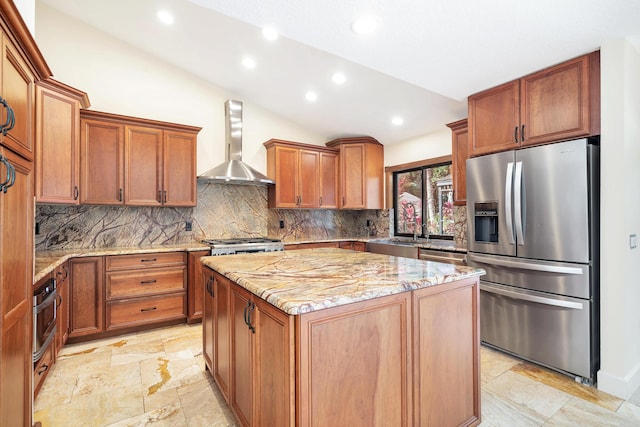 kitchen with backsplash, wall chimney range hood, a kitchen island, stainless steel appliances, and light stone counters