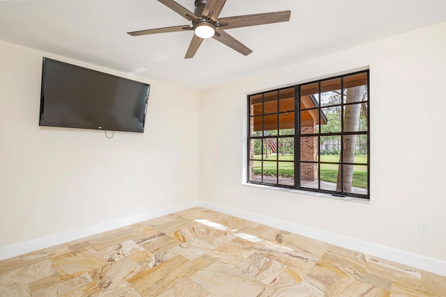 empty room featuring ceiling fan and a wealth of natural light