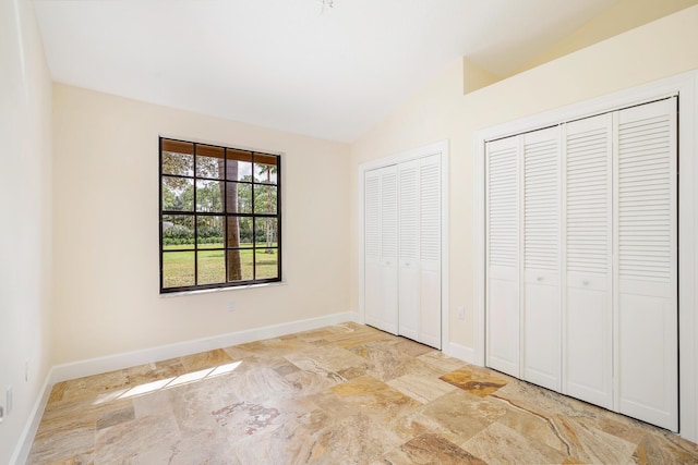 unfurnished bedroom with multiple closets and vaulted ceiling