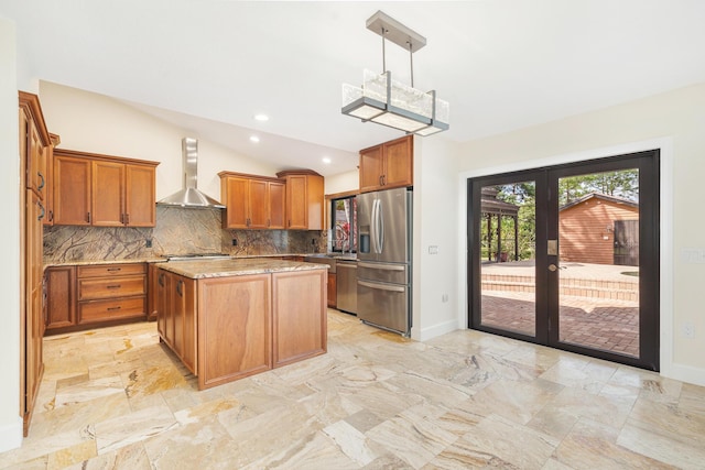 kitchen featuring wall chimney range hood, pendant lighting, a kitchen island, appliances with stainless steel finishes, and french doors