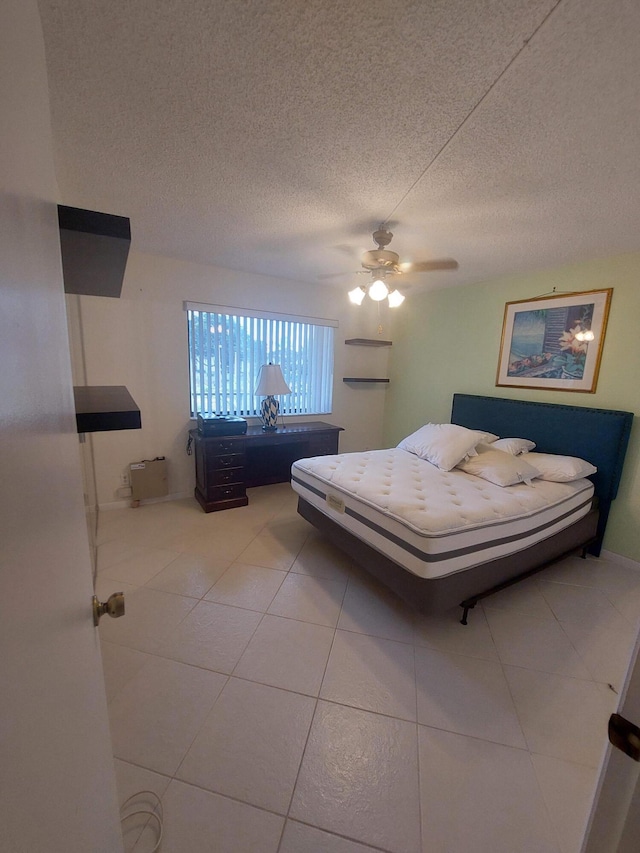 bedroom featuring ceiling fan, light tile patterned flooring, and a textured ceiling