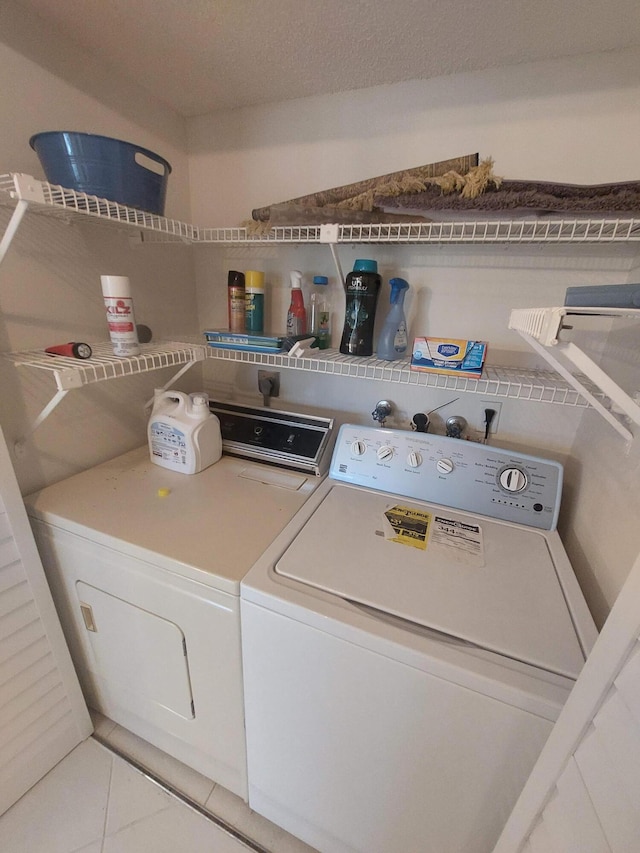 laundry room featuring light tile patterned flooring, washer and dryer, and a textured ceiling