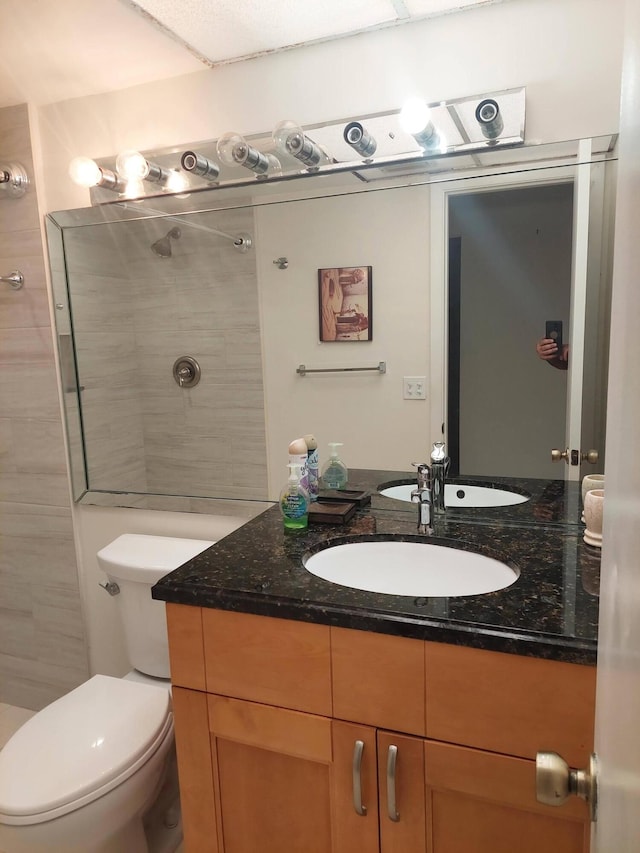 bathroom featuring tiled shower, vanity, and toilet