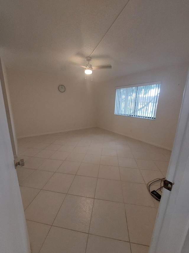 tiled spare room featuring ceiling fan