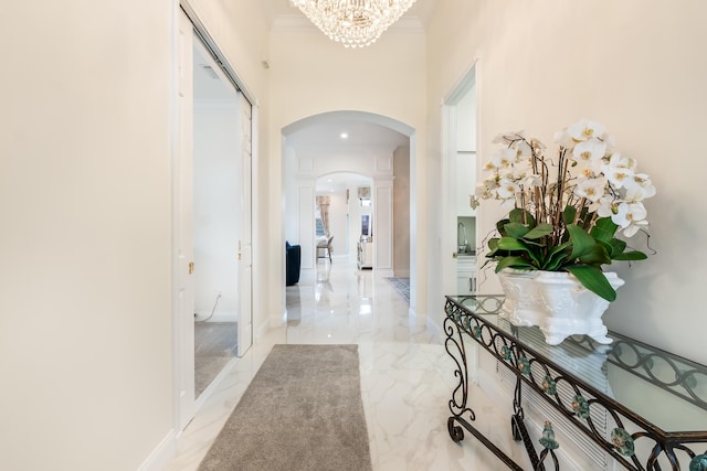 corridor featuring a chandelier, a towering ceiling, and crown molding