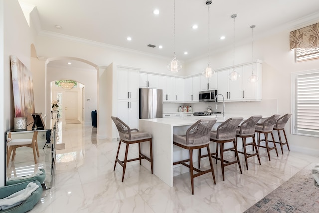 kitchen featuring white cabinets, pendant lighting, a kitchen bar, and stainless steel appliances