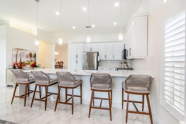 kitchen featuring white cabinets, stainless steel fridge, a kitchen bar, and pendant lighting