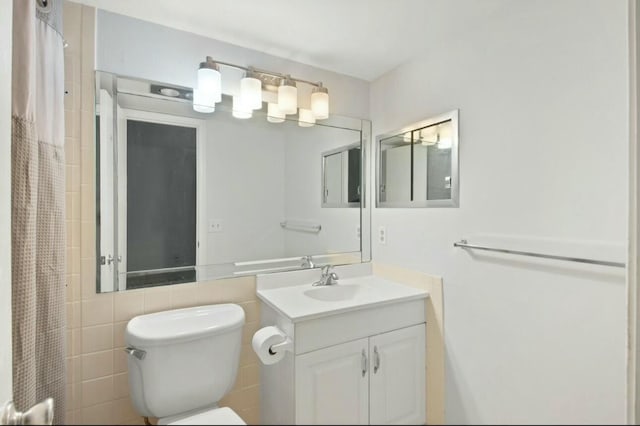 bathroom featuring vanity, curtained shower, toilet, and tile walls