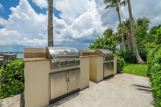 view of patio featuring exterior kitchen, a grill, and a water view