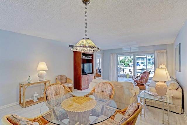 dining area with a textured ceiling and light hardwood / wood-style flooring