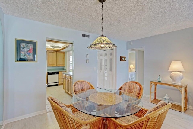 dining space with light wood-type flooring and a textured ceiling