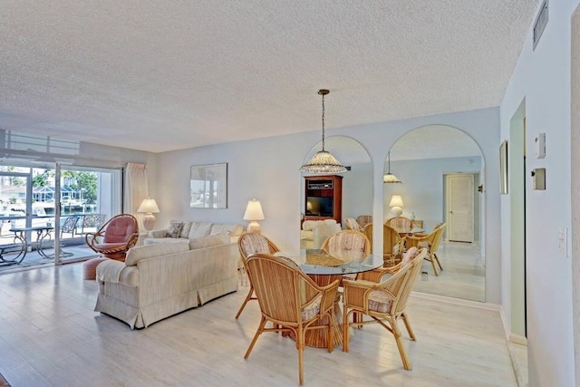 dining area with a textured ceiling and light hardwood / wood-style flooring