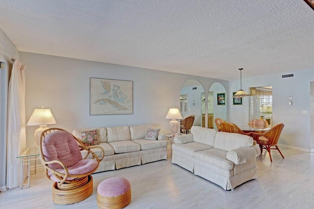 living room with light wood-type flooring and a textured ceiling