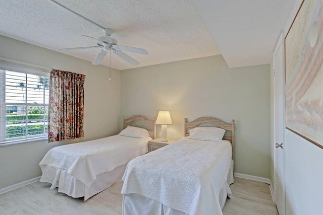 bedroom featuring ceiling fan, light hardwood / wood-style floors, and a textured ceiling