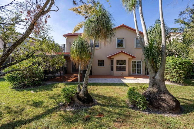 rear view of property with a balcony, a yard, and a patio