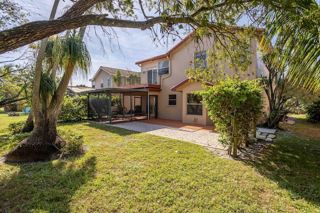 rear view of property with a yard, a sunroom, a balcony, and a patio