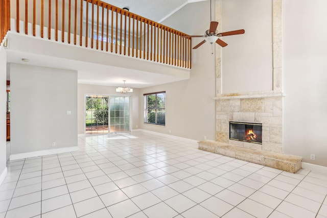 unfurnished living room with a tiled fireplace, light tile patterned floors, high vaulted ceiling, and ceiling fan with notable chandelier