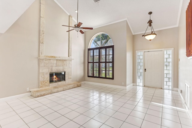 tiled foyer featuring a textured ceiling, ceiling fan, crown molding, a tile fireplace, and high vaulted ceiling