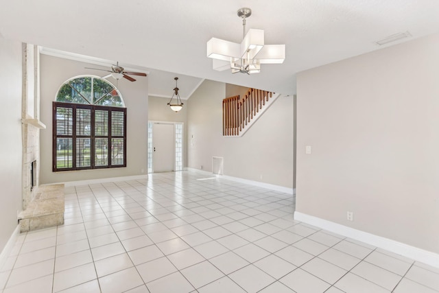 tiled empty room with ceiling fan with notable chandelier and vaulted ceiling