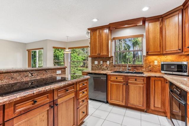 kitchen with light stone counters, plenty of natural light, black appliances, and sink