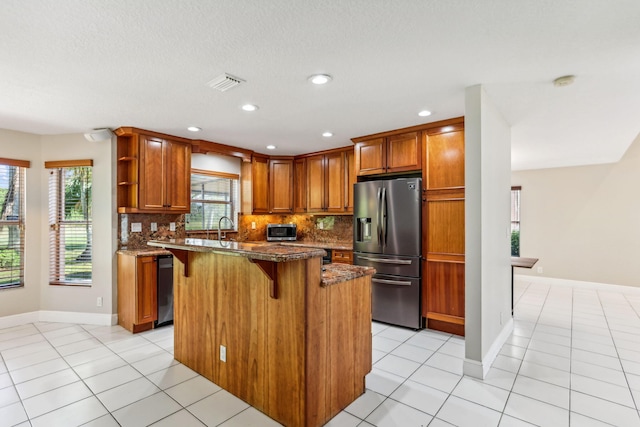 kitchen featuring dark stone countertops, decorative backsplash, a breakfast bar, a kitchen island, and appliances with stainless steel finishes