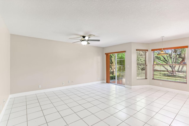 tiled spare room featuring plenty of natural light, ceiling fan, and a textured ceiling