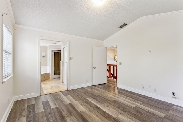 spare room with vaulted ceiling, hardwood / wood-style floors, a textured ceiling, and ornamental molding