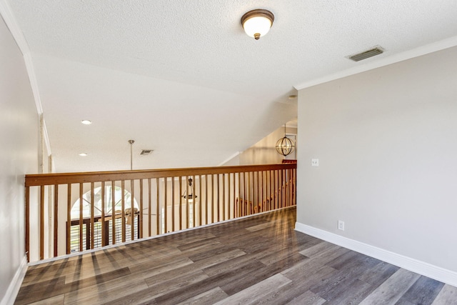 additional living space with hardwood / wood-style floors, lofted ceiling, and a textured ceiling