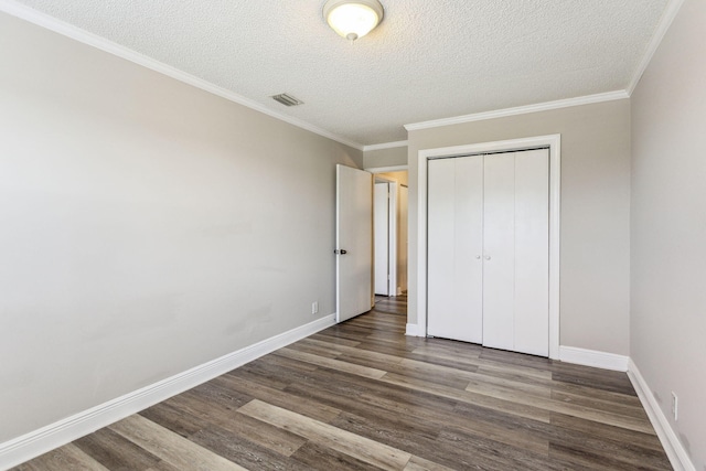 unfurnished bedroom featuring a textured ceiling, dark hardwood / wood-style floors, a closet, and ornamental molding