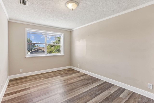 spare room featuring a textured ceiling, light wood-type flooring, and crown molding