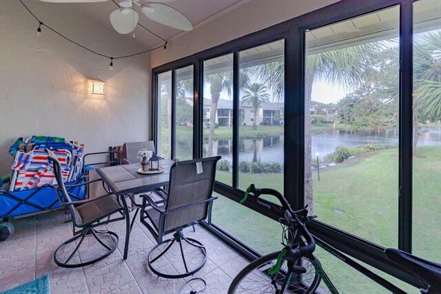 sunroom with a wealth of natural light, a water view, and ceiling fan