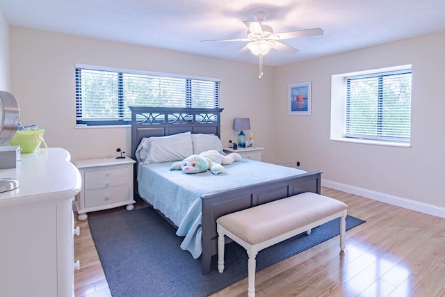 bedroom with multiple windows, ceiling fan, and light wood-type flooring