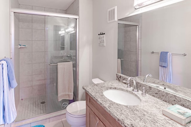 bathroom featuring tile patterned floors, vanity, toilet, and a shower with shower door