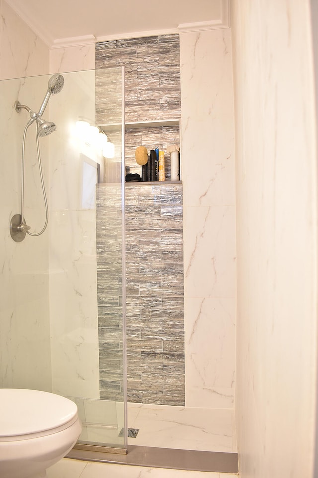 bathroom with toilet, a tile shower, ornamental molding, and tile walls