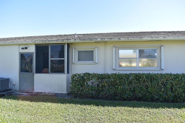 view of side of property with a lawn and cooling unit