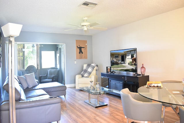 living room featuring hardwood / wood-style floors, ceiling fan, and a textured ceiling