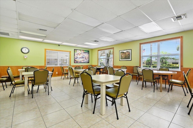 tiled dining space with a paneled ceiling and wooden walls