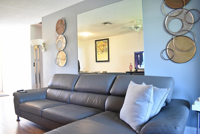 living room featuring ceiling fan, wood-type flooring, and a textured ceiling