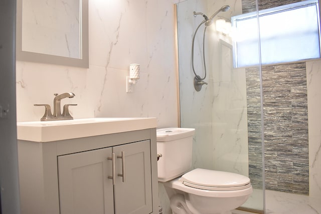 bathroom with vanity, a shower with door, toilet, and tile walls