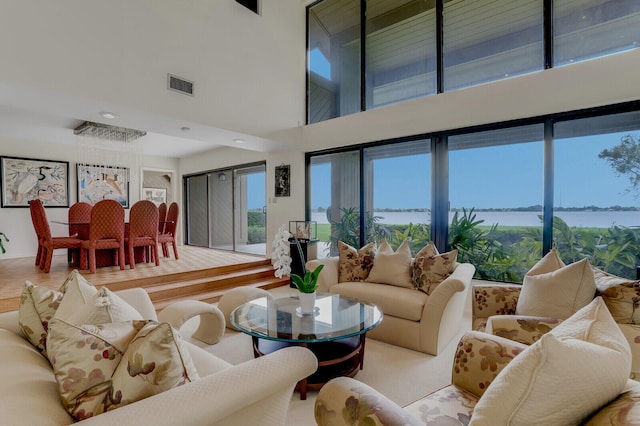 living room featuring a towering ceiling, a water view, and wood-type flooring