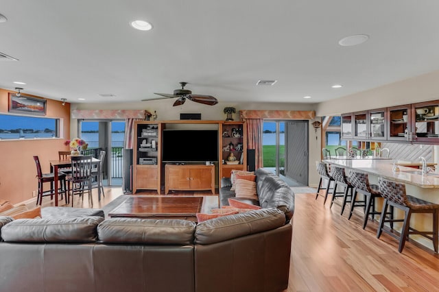 living room with ceiling fan and light hardwood / wood-style flooring