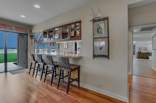 bar with stainless steel fridge, sink, and light hardwood / wood-style flooring