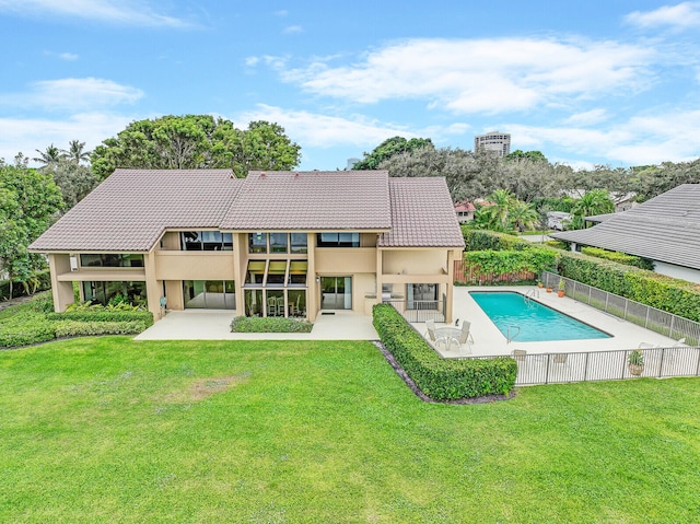 back of property featuring a fenced in pool, a patio area, and a lawn