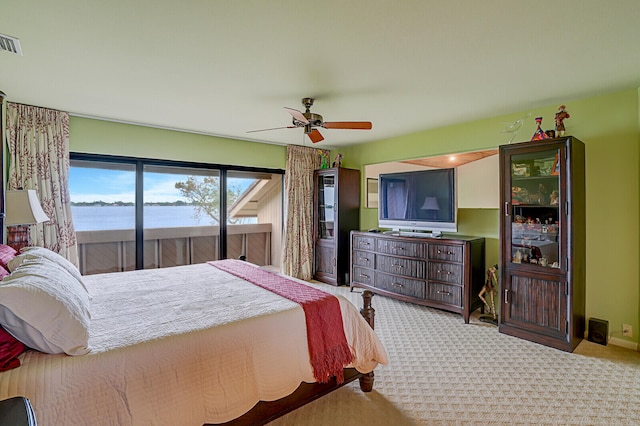 bedroom with a water view, ceiling fan, and light colored carpet