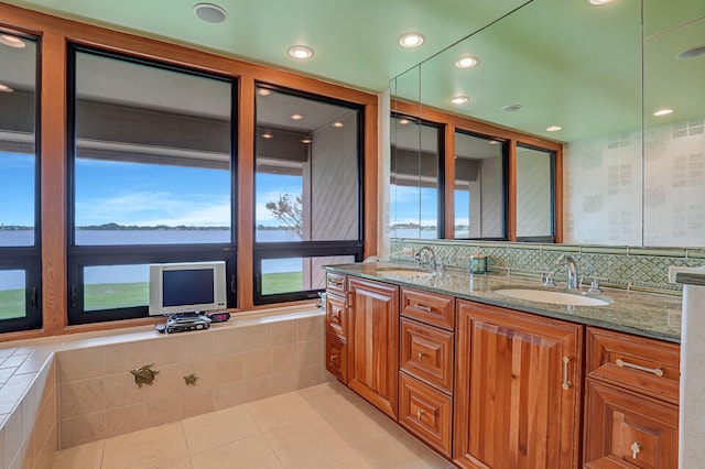 bathroom with tile patterned flooring, vanity, tasteful backsplash, and tiled bath