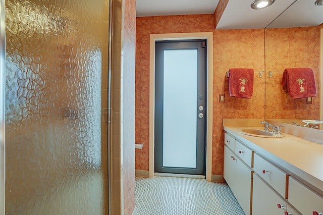 bathroom with a shower with door, vanity, and tile patterned flooring