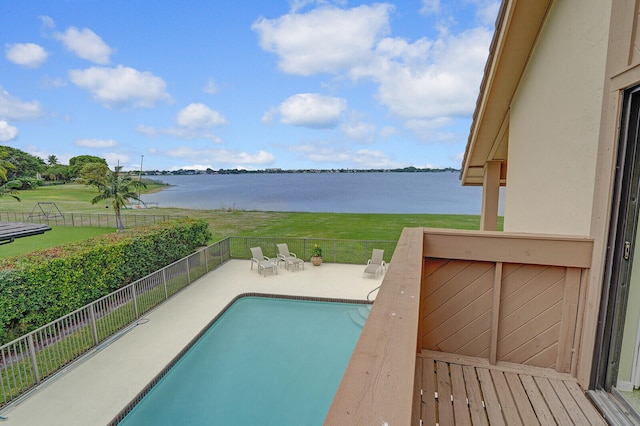 view of pool featuring a water view, a patio area, and a lawn