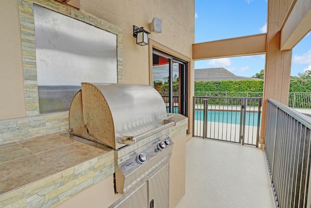 view of patio featuring a grill, a fenced in pool, and exterior kitchen