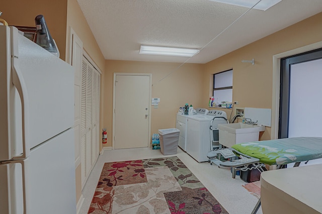 laundry area with light carpet, a textured ceiling, washer and clothes dryer, and sink